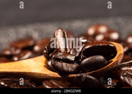 Close-up of brown, roasted coffee beans in a wood spoon background. Stock Photo