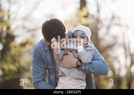 Happy cute daughter on father's hand. Dad and daughter walk in the park. Family mood. Little gil laugh Stock Photo