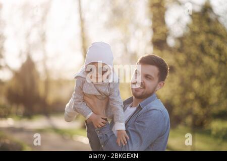 Happy cute daughter on father's hand. Dad and daughter walk in the park. Family mood. Little gil laugh Stock Photo