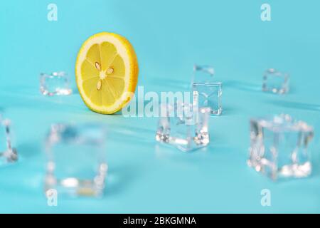 Creative layout made of yellow lemon wheel and ice cube on blue color background. Trendy summer pattern. Minimal fashion concept. Close up. Stock Photo