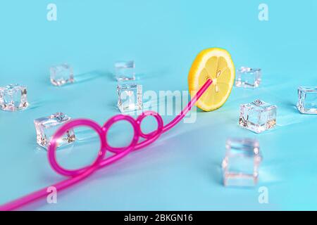 Creative layout made of yellow lemon wheel and ice cube on blue color background. Trendy summer pattern. Minimal fashion concept. Close up. Stock Photo