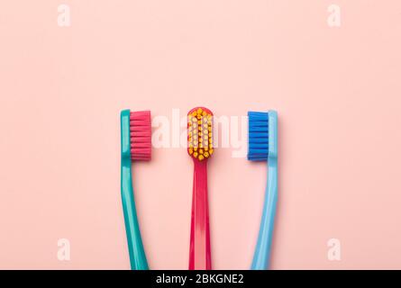 Toothbrushes of different colors on a pink background. Brushing teeth and oral hygiene. Stock Photo