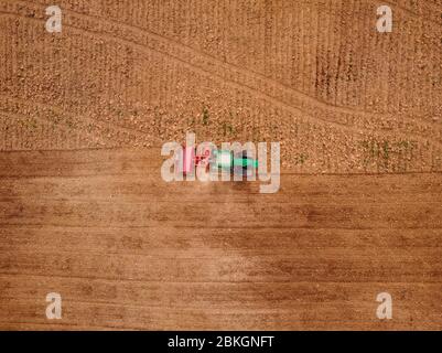 Agriculture tractor plows field of land for sowing. Top view aerial photo Stock Photo