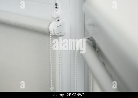 Details of white fabric roller blinds on the plastic window with wood texture in the living room. Stock Photo