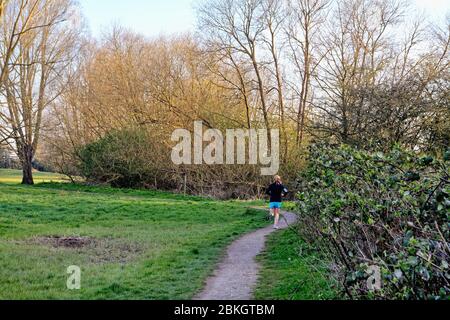 A rear view of a female runner exercising on a footpath in the countryside Shepperton Surrey UK Stock Photo