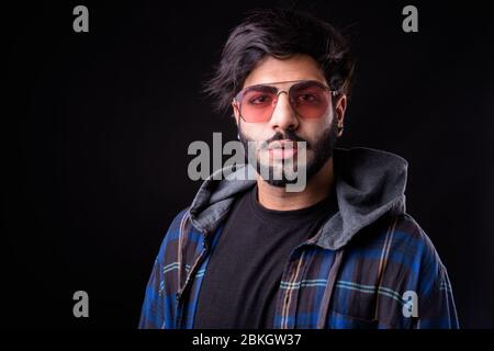 Portrait of young handsome bearded Indian hipster man with sunglasses Stock Photo