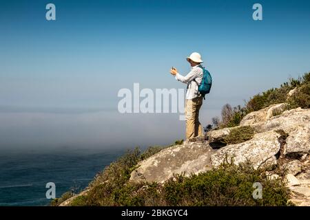 South Africa, Western Cape, Plettenberg Bay, Robberg Nature Reserve, Cape Seal, tourist on path above rocky coastline Stock Photo