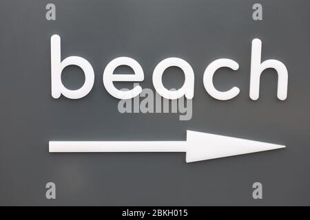 The white word beach of hanging on a gray wall. pointer arrow beach right Stock Photo