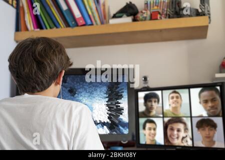 Teenage boy video chatting on the computer with friends at home Stock Photo