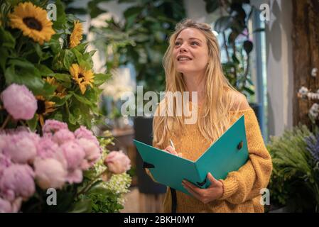 Young woman writing in flower shop Stock Photo