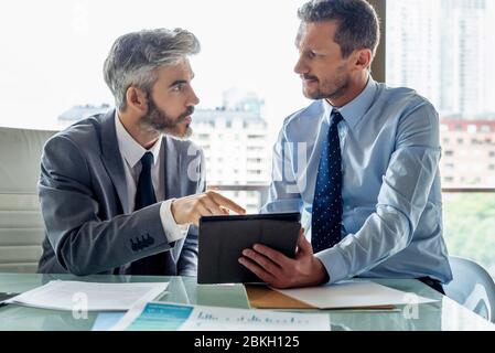 Businessmen discussing over digital tablet Stock Photo