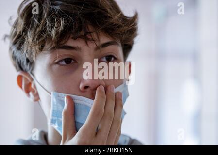 Close up of teenage boy wearing blue surgical mask Stock Photo