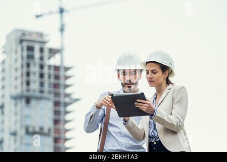 Architects using digital tablet at construction site Stock Photo