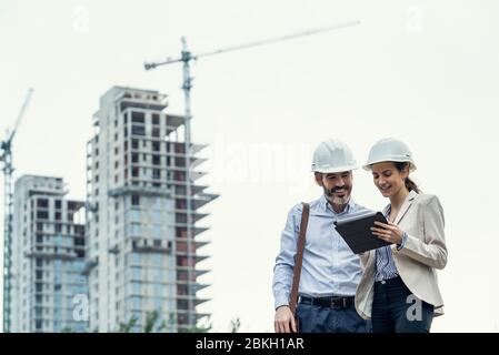Architects using digital tablet at construction site Stock Photo