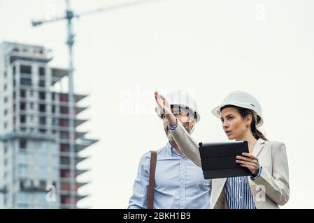 Architects talking with each other at construction site Stock Photo