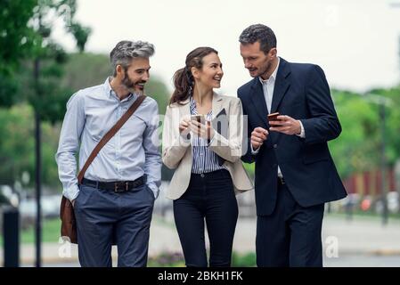 Business people using smartphones in public park Stock Photo