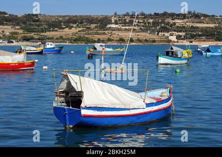 Colourful boats from the fishing fleet in Marsaxlokk, Malta are moored in the harbour. The traditional village is popular with tourists. Stock Photo