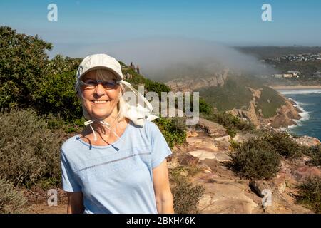 South Africa, Western Cape, Plettenberg Bay, Robberg Nature Reserve, senior tourist on coastal hiking trail, as sea mist rolls in behind Stock Photo