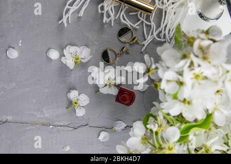 Cosmetic set on grey dressing table. Top views with clear space. White flowers, earrings and lipstick Stock Photo