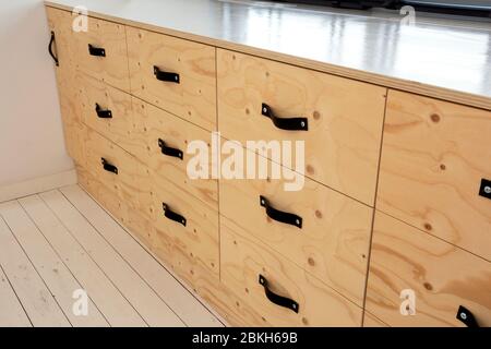 Modern wooden storage drawers in retro home with leather handles, Stock Photo