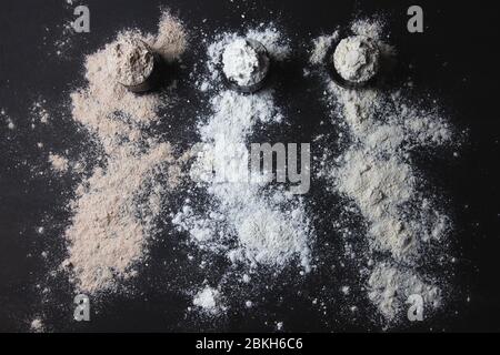Three jars full of different types of flour, gluten free alternatives, sprinkled flour, black background Stock Photo