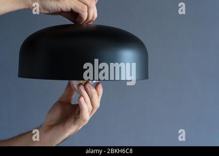 Close-up. A hand changes a light bulb in a stylish loft lamp. Spiral filament lamp. Modern interior decor Stock Photo