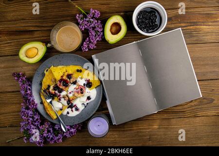 Pancakes with berries and bananas on a grey plate with blank notepad over dark wooden background, top view. From above, flat lay, overhead Stock Photo