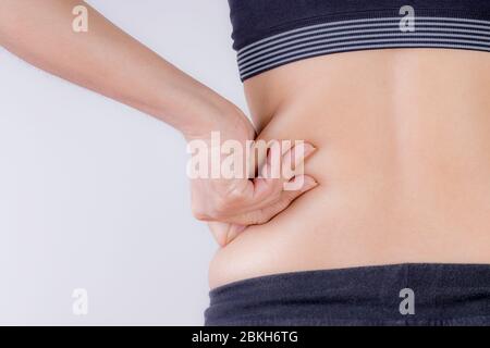 Fat woman hand holding excessive belly fat. Healthcare and woman diet lifestyle concept to reduce belly and shape up healthy stomach muscle. Stock Photo