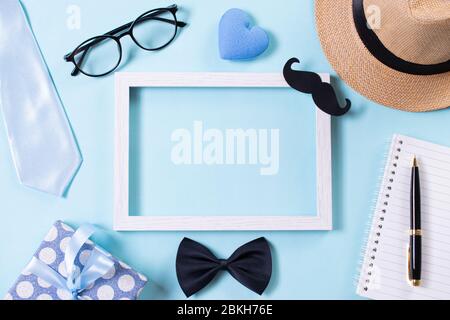 Happy fathers day concept. Top view of tie, beautiful gift box, hat, white picture frame with Happy father's day text on bright blue pastel background Stock Photo