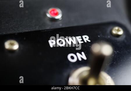 Economy stimulation and lockdown termination concept: View beyond joystick of retro control panel on text "power on" and red light (focus on letter "w Stock Photo