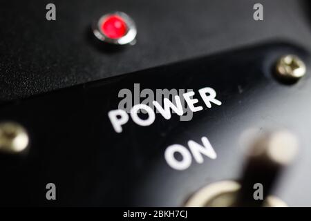 Economy stimulation and lockdown termination concept: View beyond joystick of retro control panel on text "power on" and red light (focus on letter "w Stock Photo