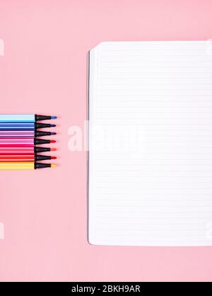 Desk Photo template with copy space Notebook and several multi-colored markers are lying on a pink background Stock Photo