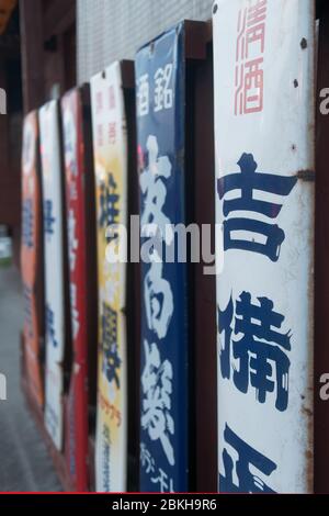 Japanese traditional signs of Sake (rice wine) hanging on the exterior wall of a liquor shop. Stock Photo