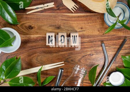 The wooden brick with words ' NOW ' on wooden background. ECO concept with recycling symbol and leaves. Stock Photo