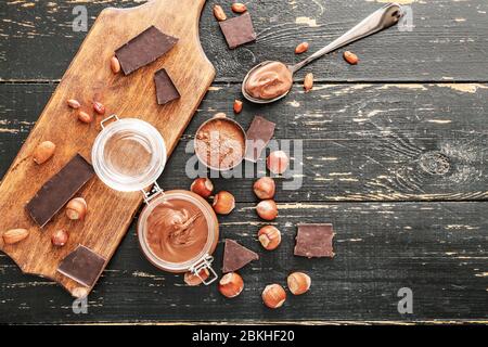 Jar with tasty chocolate paste and hazelnuts on table Stock Photo