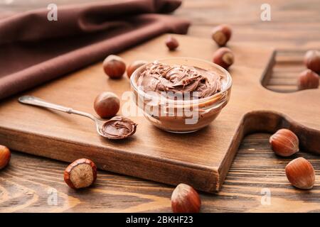Bowl with tasty chocolate paste and hazelnuts on table Stock Photo