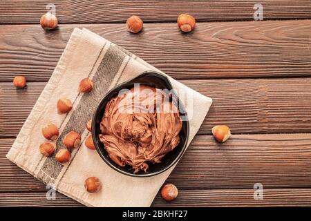 Bowl with tasty chocolate paste and hazelnuts on table Stock Photo