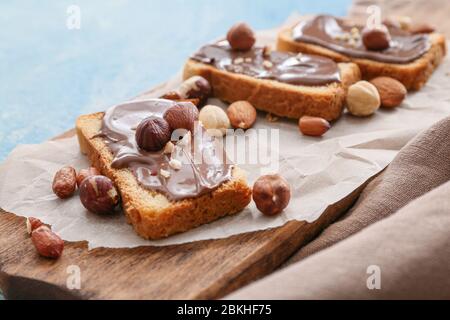 Fresh bread and chocolate paste and nuts on board, closeup Stock Photo