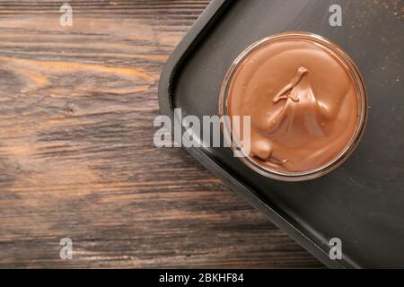 Bowl with tasty chocolate paste and hazelnuts on table Stock Photo