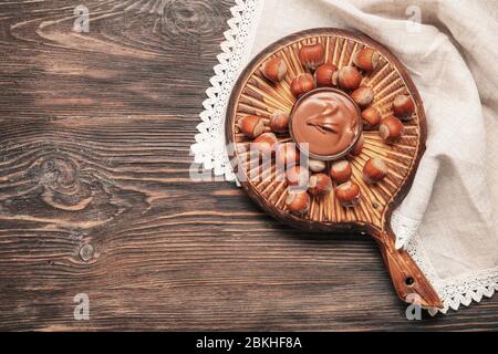 Bowl with tasty chocolate paste and hazelnuts on table Stock Photo