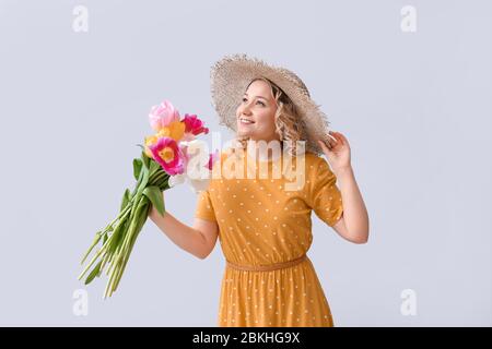 Beautiful young woman with bouquet of flowers on light background Stock Photo