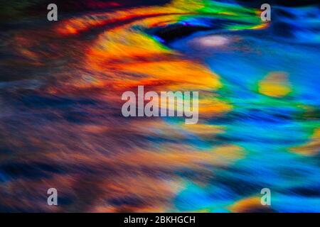 A rainbow of colors being reflecting in water with small waves and ripples. Stock Photo