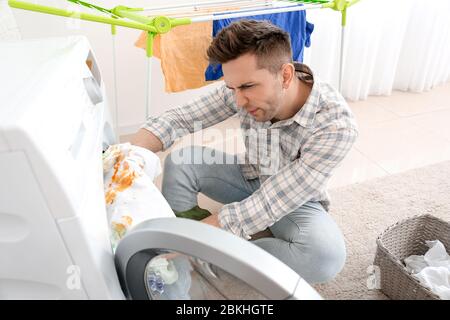 Troubled man doing laundry in bathroom Stock Photo