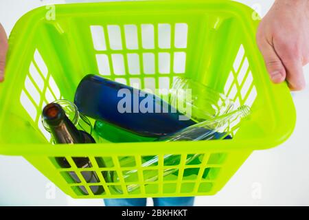 Young man isolated over white background. Close up and cut view of hands holding green plastic basket. Colorful glasses bottles lying inside Stock Photo