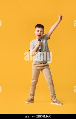 Cute little boy singing against color background Stock Photo