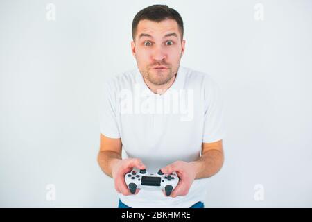 Young man isolated over white background. Guy hold joystick in hands and play computer game. Concentrated on playing. Stock Photo