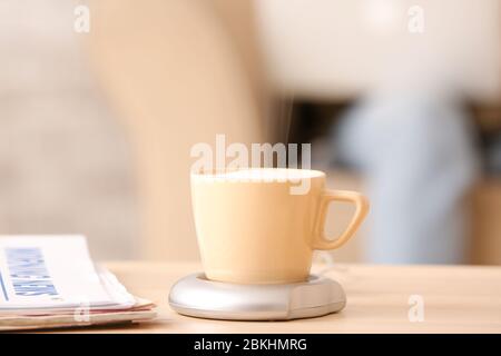 Cup of coffee with heater and newspaper on table Stock Photo