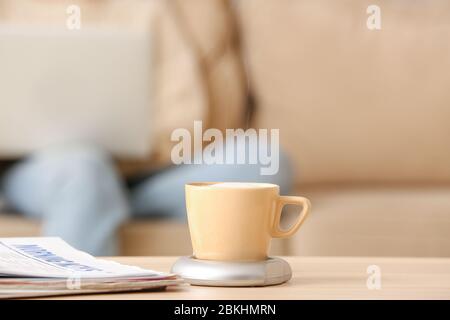 Cup of coffee with heater and newspaper on table Stock Photo