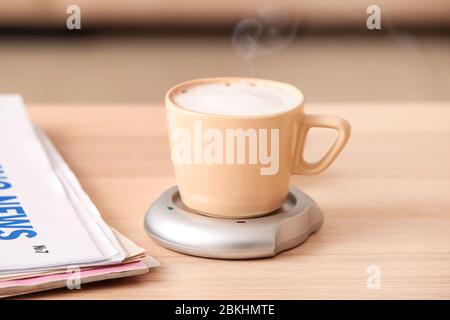 Cup of coffee with heater and newspaper on table Stock Photo