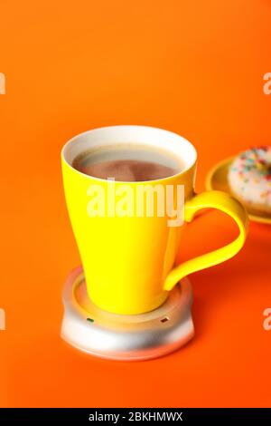 Cup of coffee with heater on color background Stock Photo